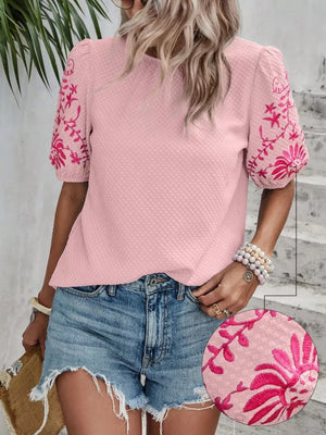 Pink embroidered puff sleeve blouse with textured fabric and floral sleeve detail.
