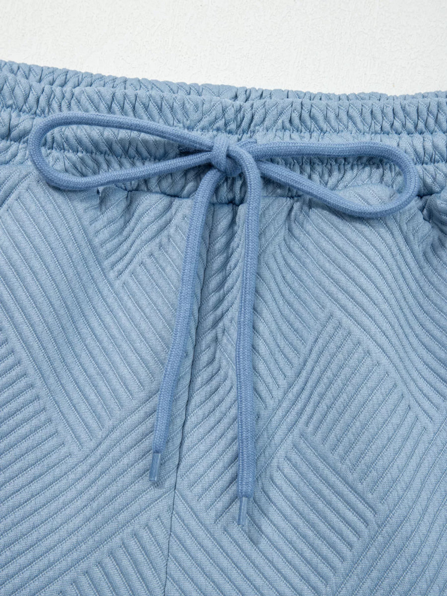 Light blue textured drawstring shorts with elastic waistband and geometric pattern.