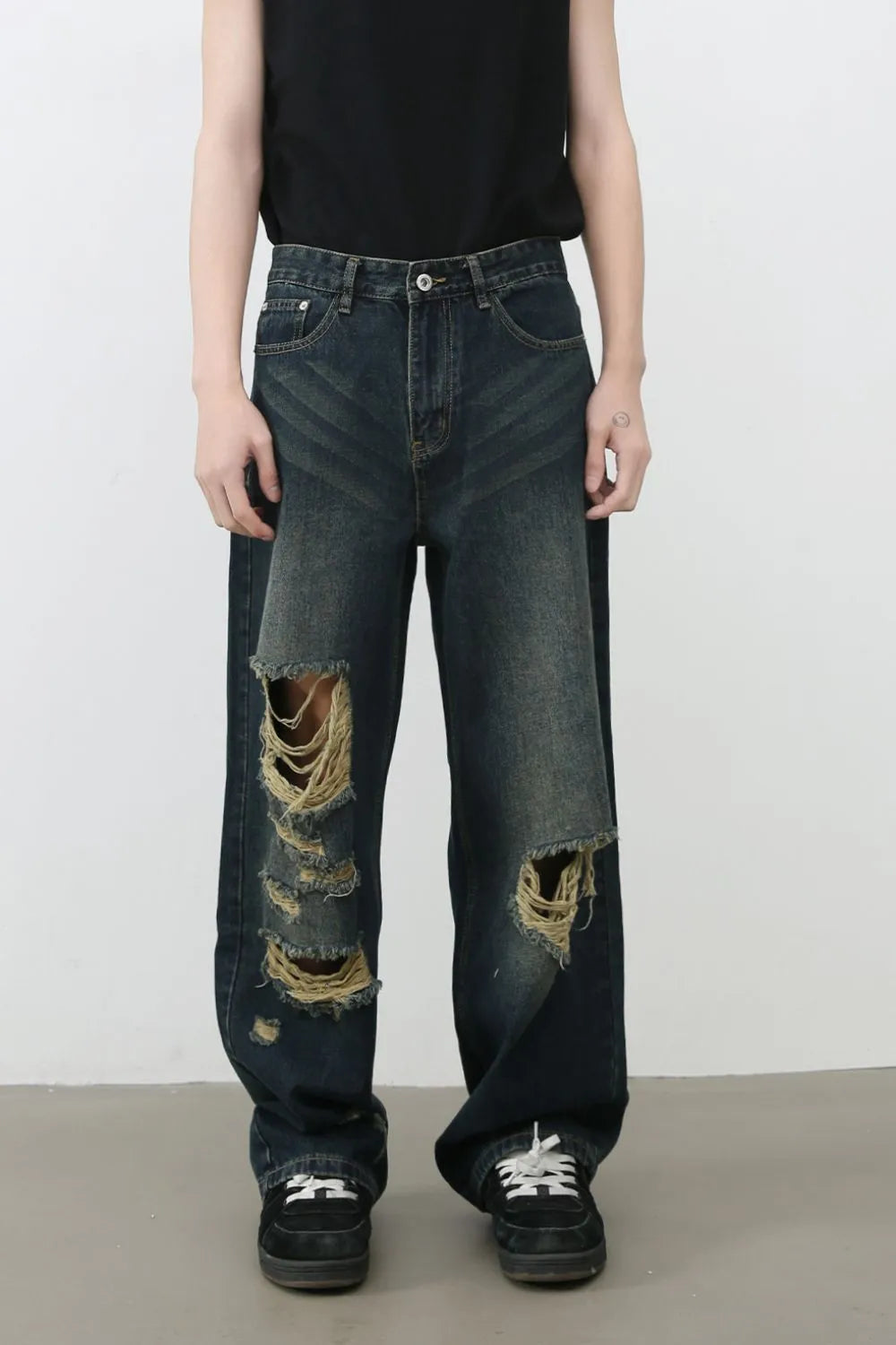 Dark distressed wide-leg denim jeans with knee tears and chevron stitching detail.