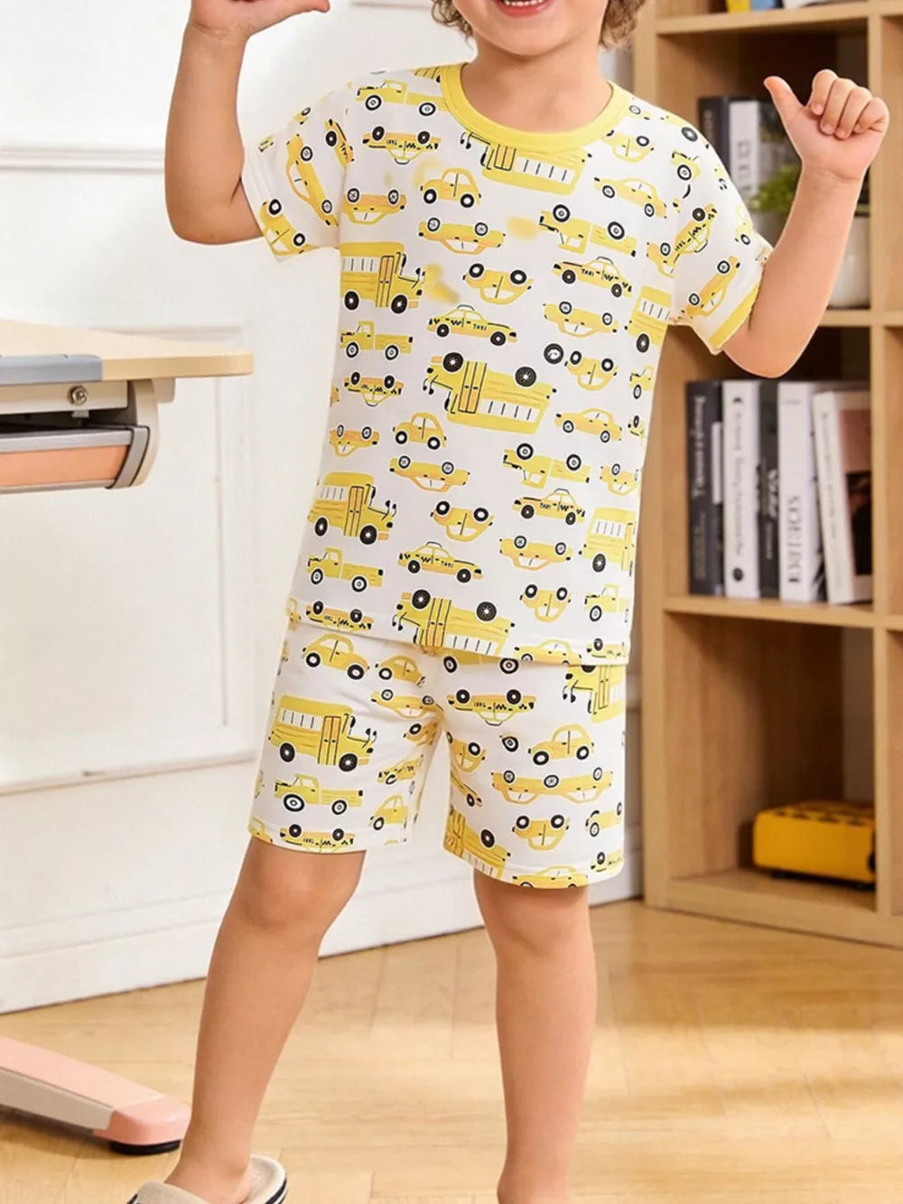 Toddler pajama set with yellow cartoon cars on white, crew neck, short sleeves, and shorts.
