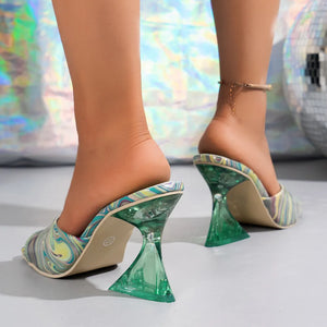 Swirl print lucite heel mules with a multi-color pattern and clear green geometric heels.