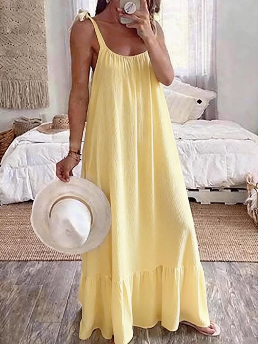 Yellow tie strap maxi dress with ruffled hem and textured fabric.