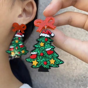 Festive Christmas tree dangle earrings with red bows and Santa hats, green glitter, red ornaments, yellow stars.