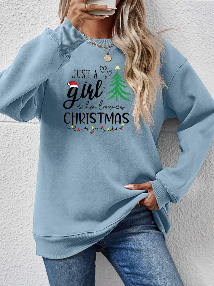 Misty Blue sweatshirt with "Just a girl who loves Christmas" graphic and festive lights.