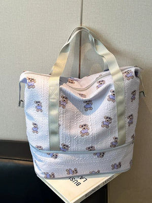 Tote bag with allover teddy bear print, light blue textured fabric, and grey straps.