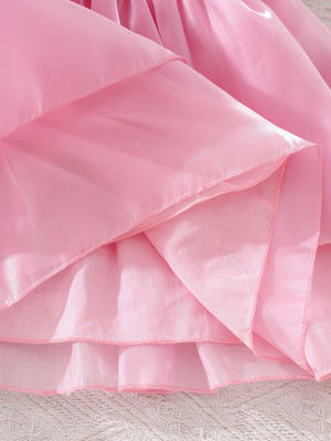Pink baby dress with tiered skirt and ruffled hem detail.