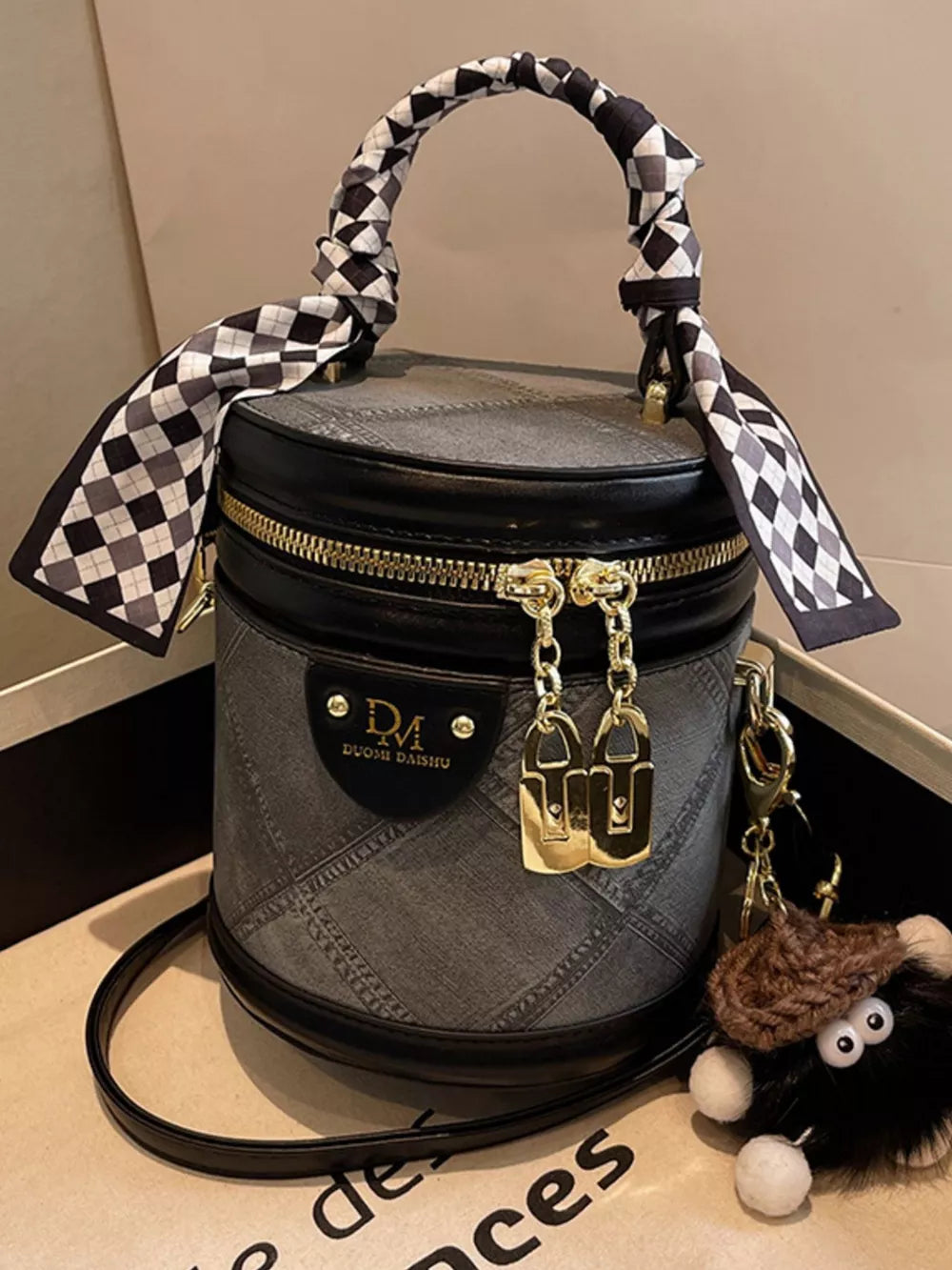Quilted mini bucket bag in black with checkered scarf detail and gold hardware.