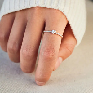 Silver ring with a heart-shaped stone and small accent stones on the band