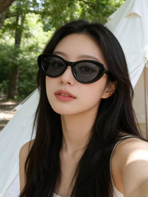 Black cat eye sunglasses with UV protection worn by a woman outdoors.