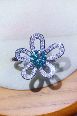 Teal moissanite ring with diamond accents in a flower halo design.