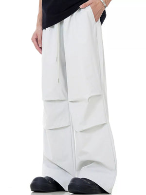 Men's beige wide-leg drawstring jogger pants with layered cargo pockets.