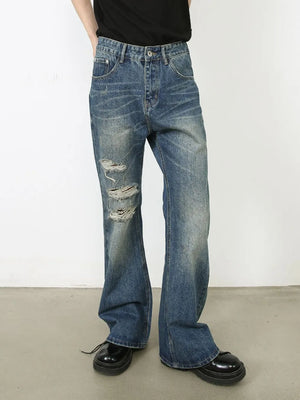 Distressed flare leg jeans in medium wash denim with ripped details.