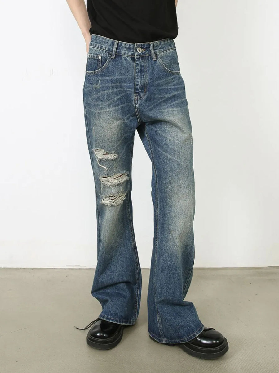 Distressed flare leg jeans in medium wash denim with ripped details.