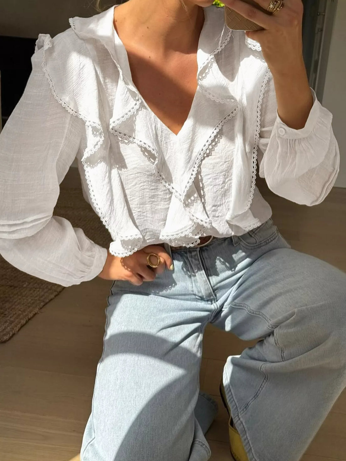 White lace ruffle V-neck blouse with long sleeves and lace trim details.