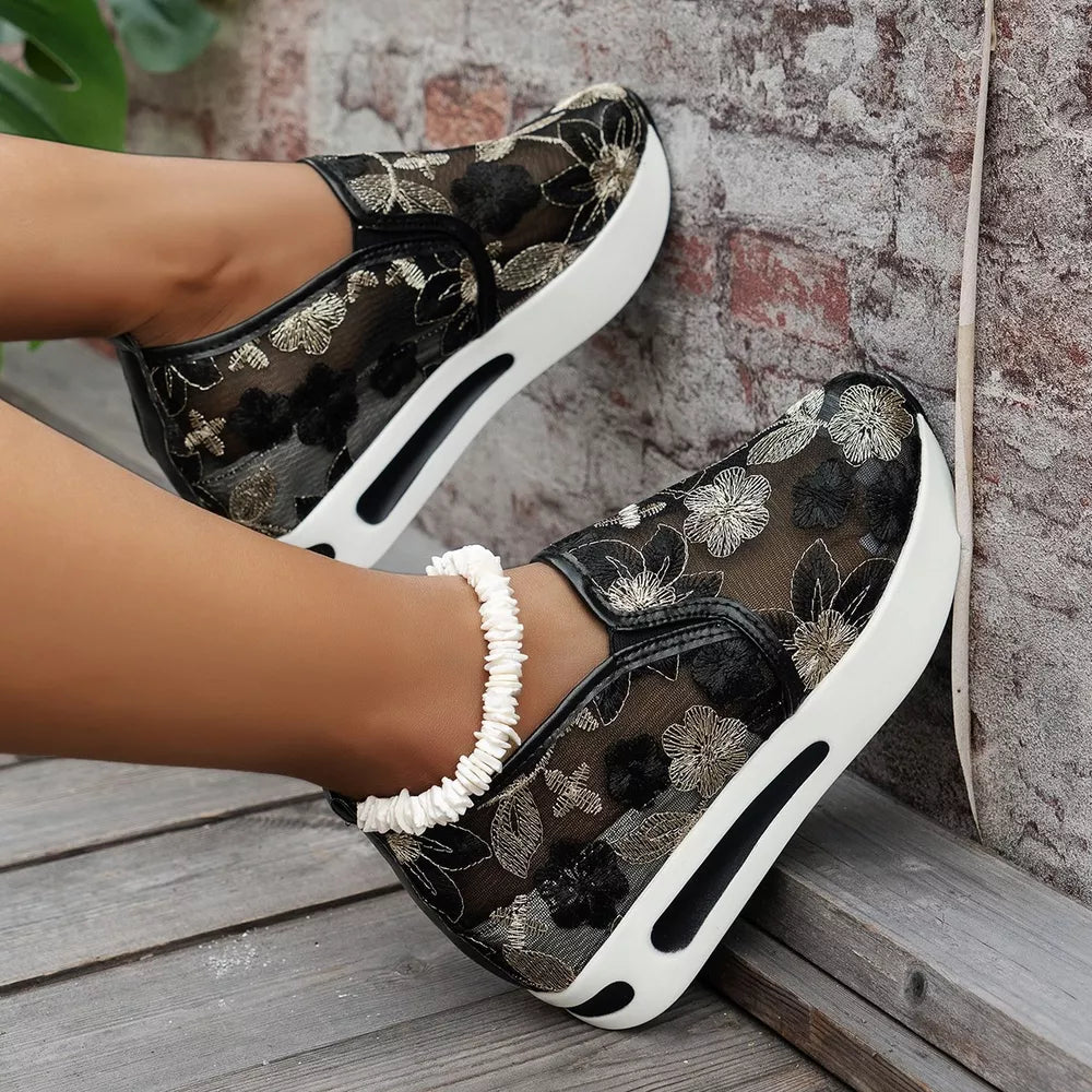 Black floral embroidered mesh slip-on sneakers with chunky white platform sole.