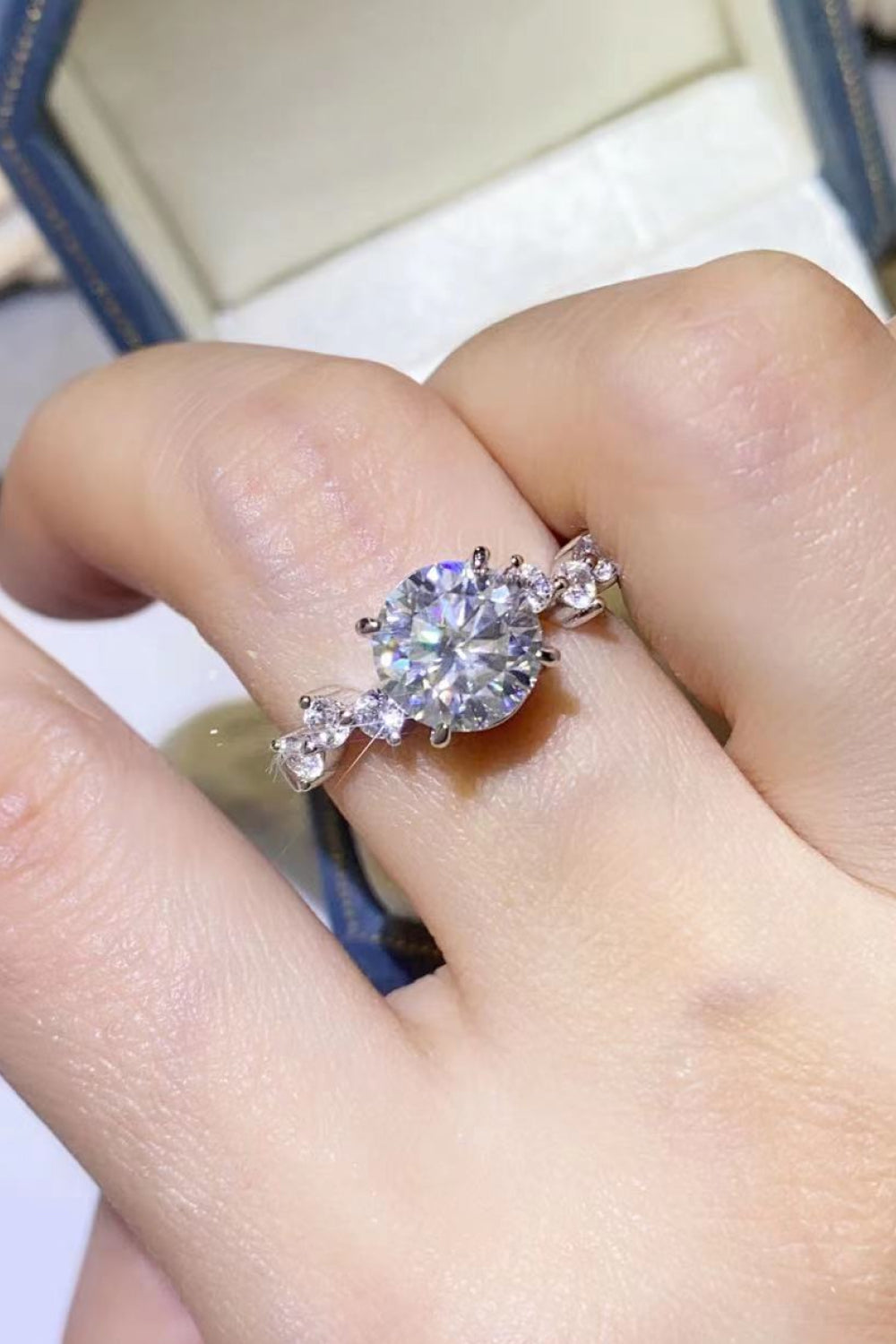 Silver moissanite halo ring with delicate blossom accents.