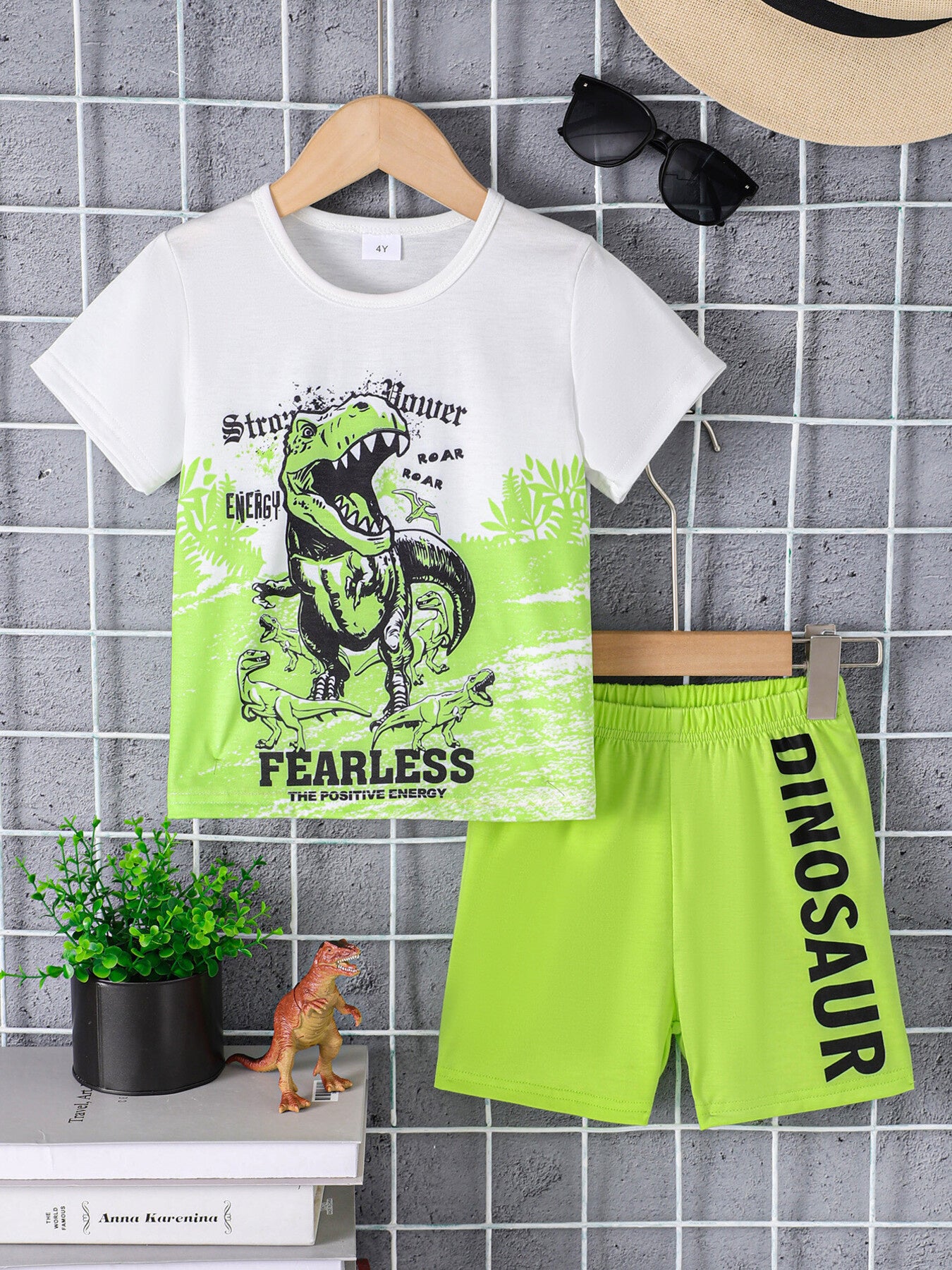 White crew neck t-shirt with dinosaur graphic and green shorts with dinosaur text