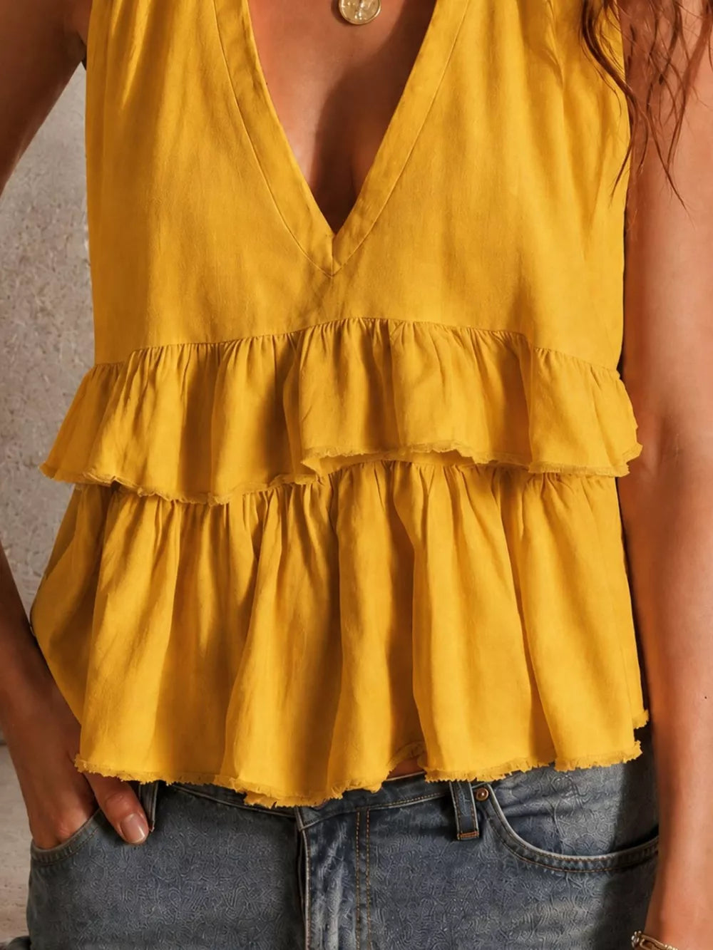 Gold ruffled V-neck tank top with layered tiers and raw hem.
