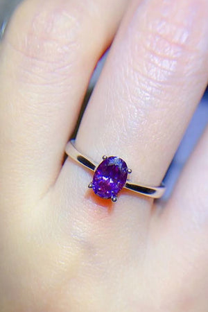 Oval cut amethyst solitaire ring with a purple gemstone on a silver band.