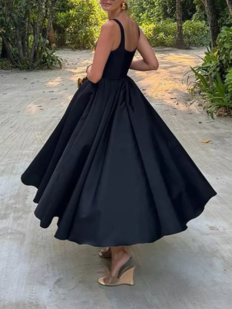 Black a-line midi dress with square neckline and full skirt, worn by a woman.