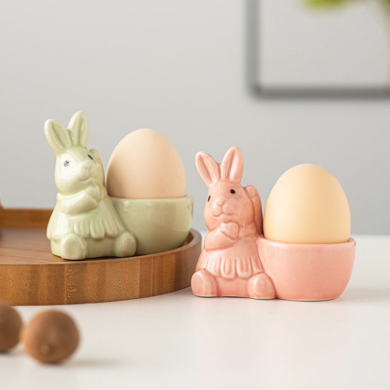 Ceramic bunny egg holders in blush pink and light green, each holding an egg.