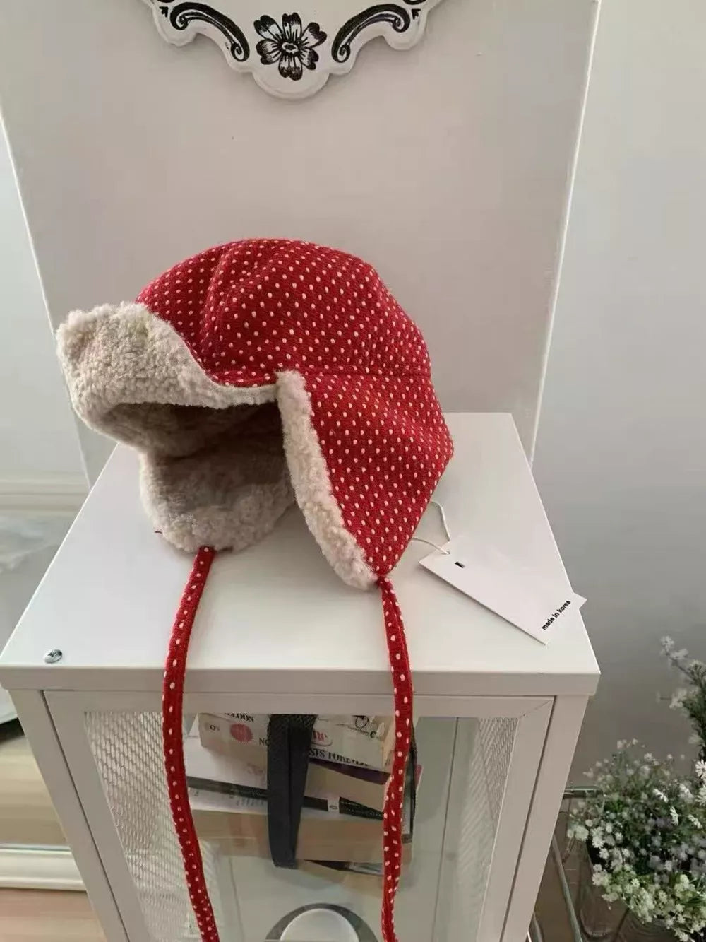 Red polka dot fleece hat with cream lining and ear flaps with ties.