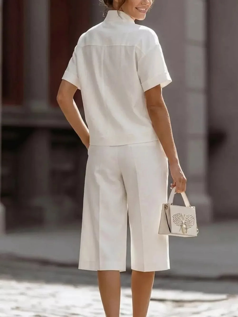 White two-piece set with pocketed top and wide-leg cropped pants, styled with a handbag.