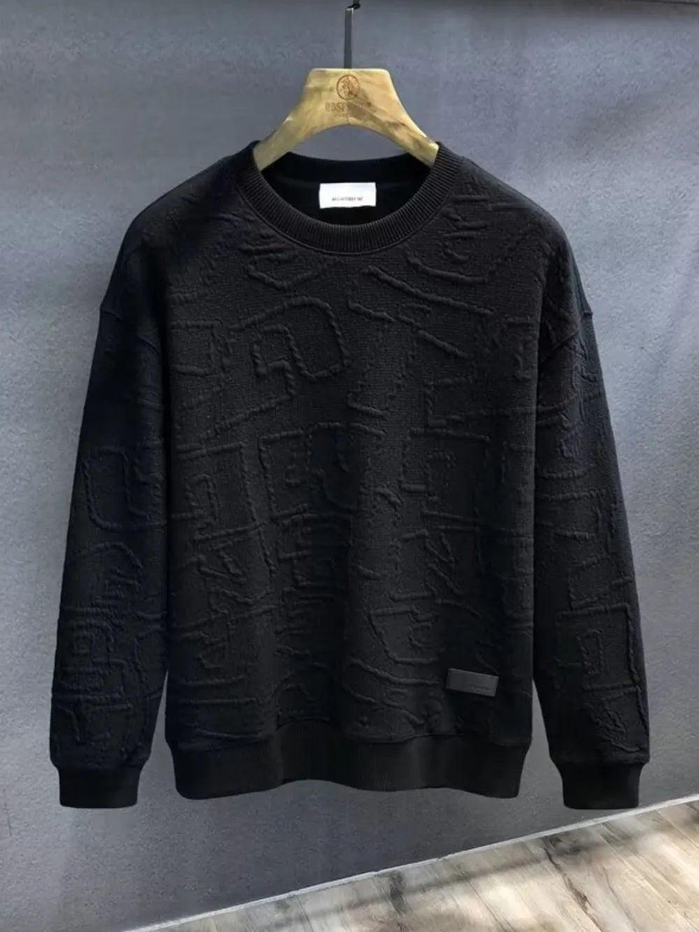 Black crewneck sweatshirt with embossed geometric texture and ribbed cuffs and hem.