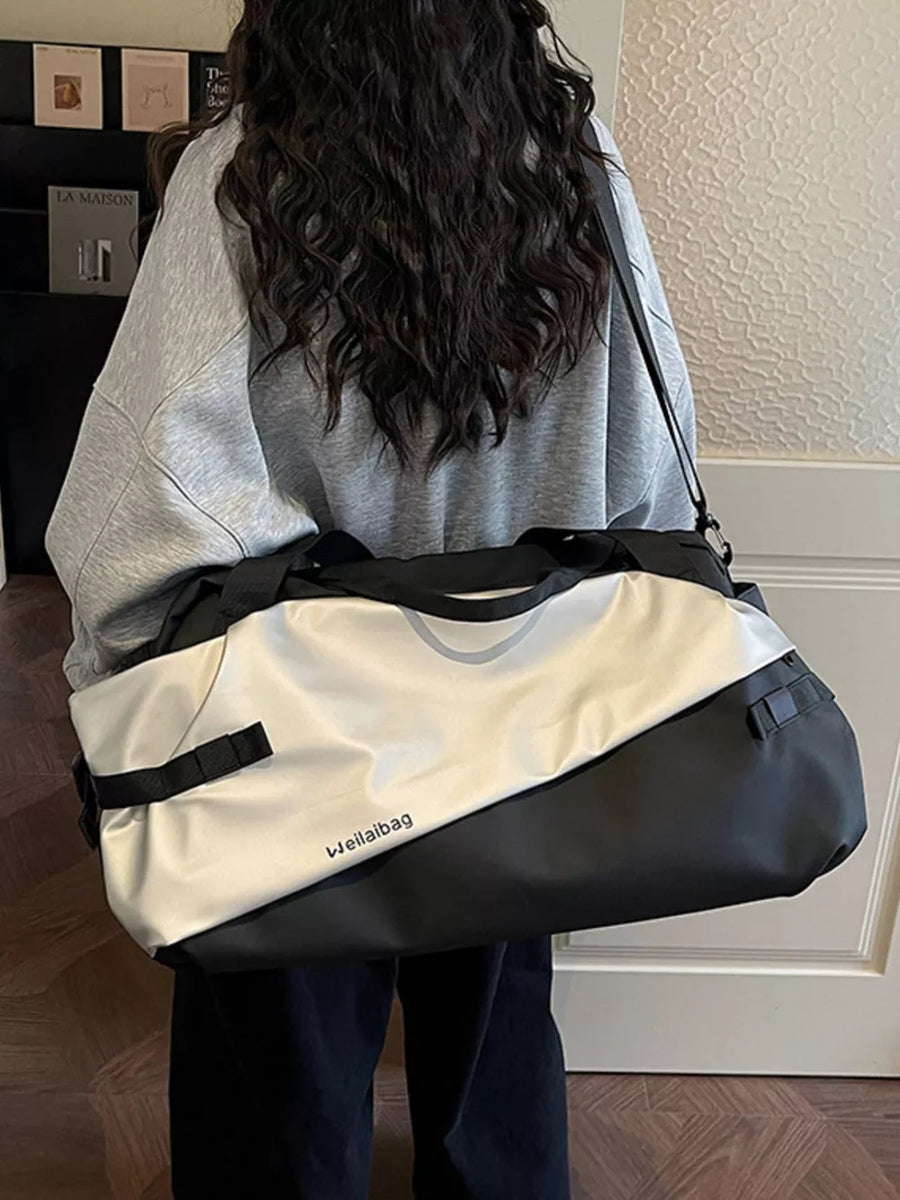 Oxford cloth travel bag in black and silver with diagonal color block design and side straps.