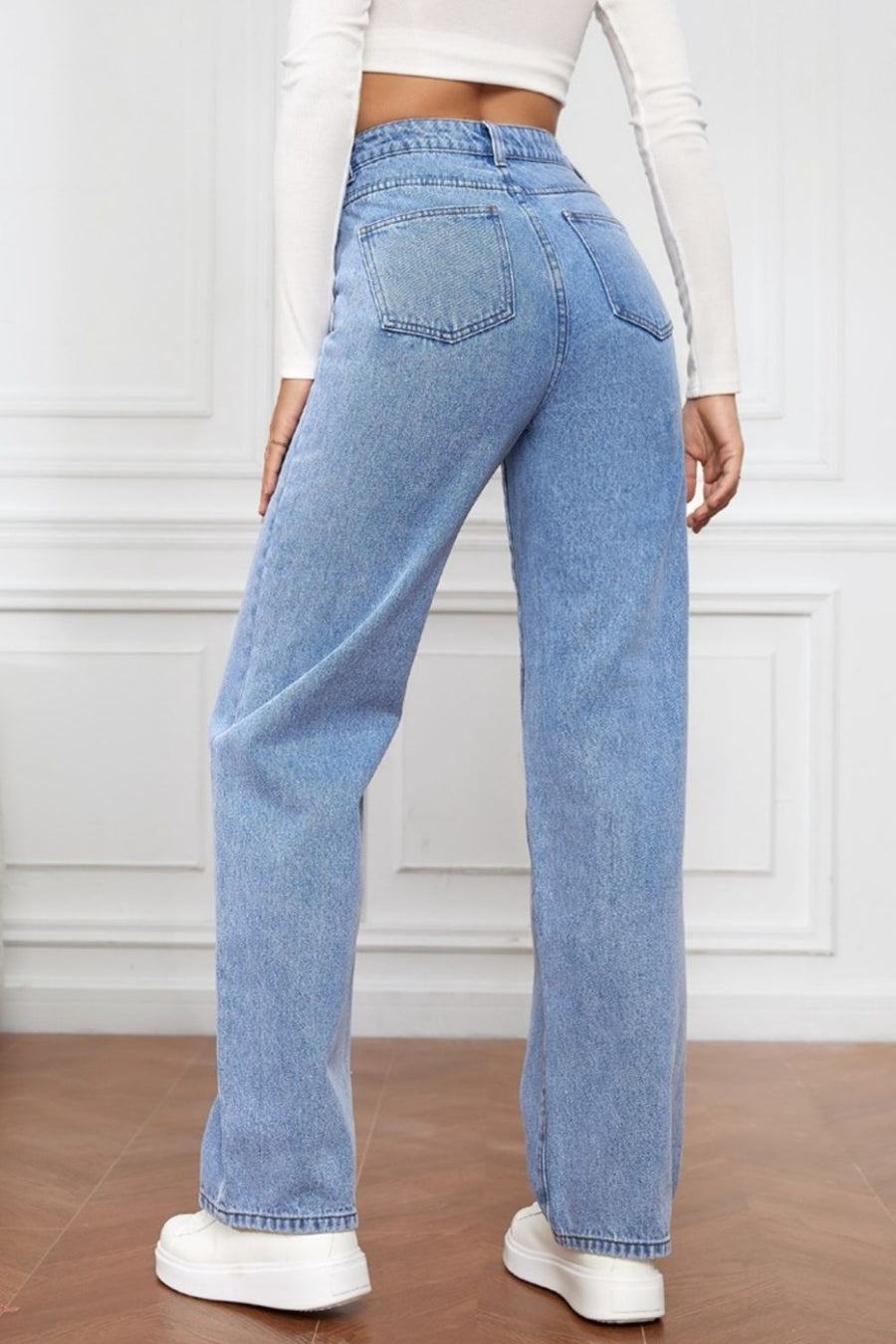 Light blue denim jeans with a wide leg and sculpted waist, shown from the back.