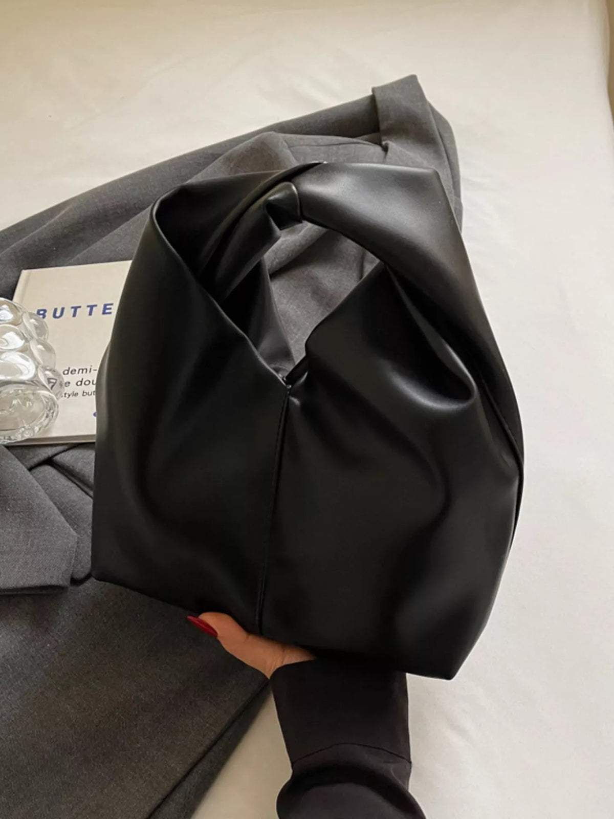Black leather shoulder bag with a unique knot handle