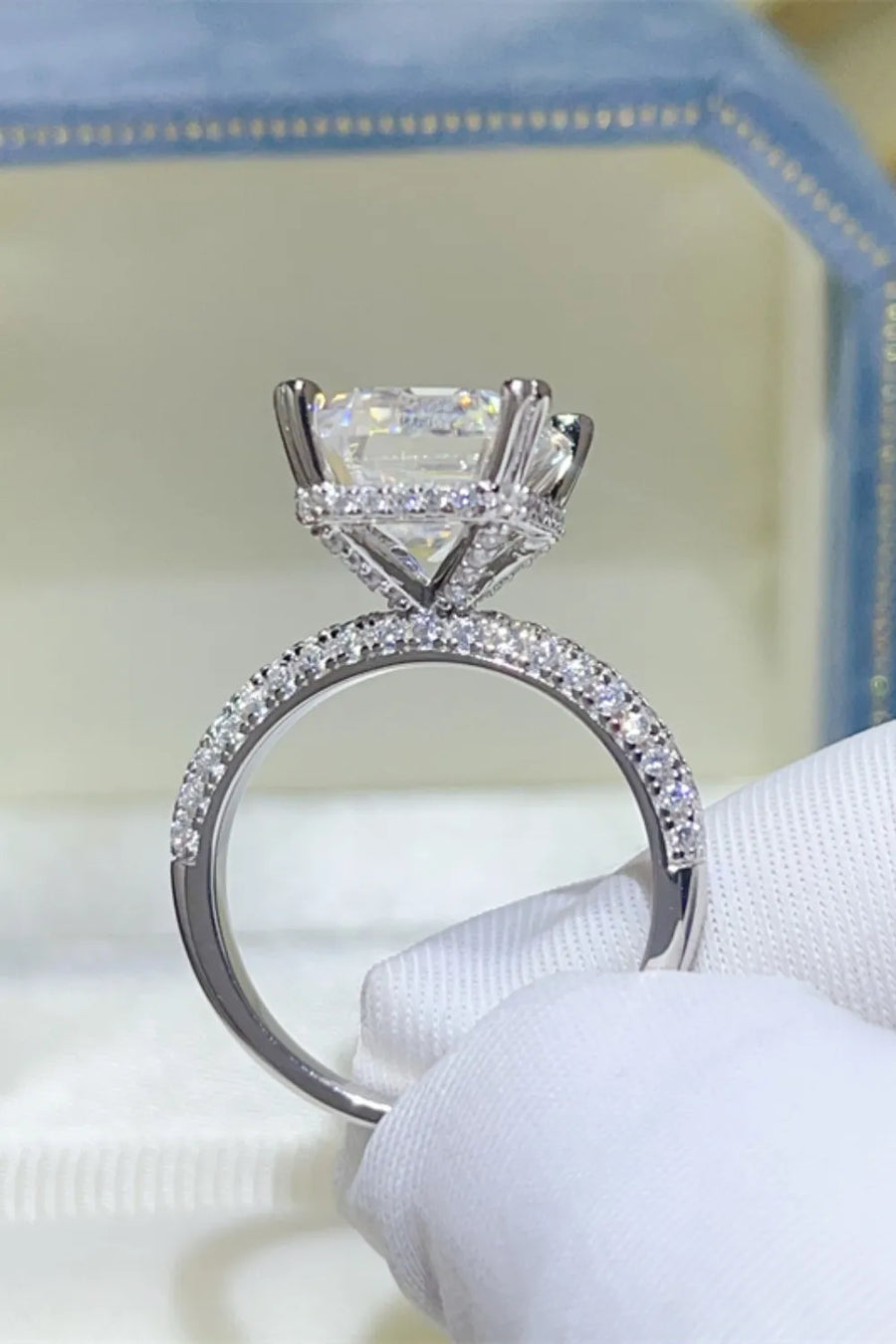 Emerald cut moissanite ring with pave diamond band in silver.