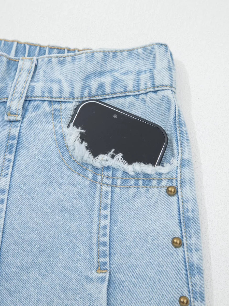 Light wash denim jeans with studded side detail and frayed pocket.
