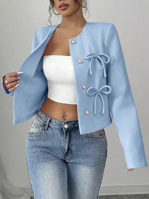 Light blue textured jacket with pearl buttons and bow details, round neckline, long sleeves.