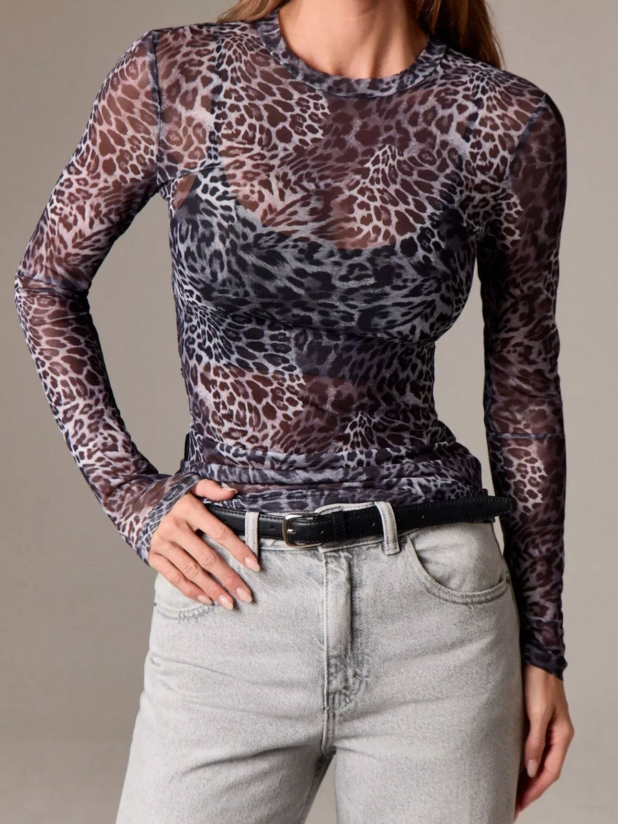 Sheer long-sleeve top with leopard print and crew neck, styled with jeans.