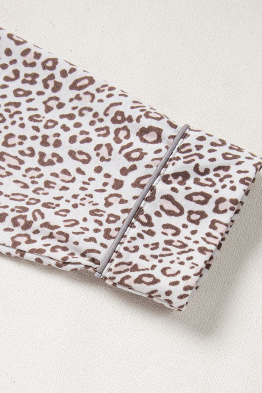 Leopard print pajama set with button-down detail and grey piping on cuff.