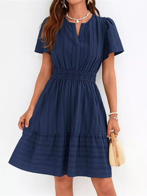 Navy textured V-neck tiered dress with smocked waist and short sleeves.