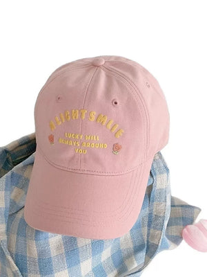 Pink baseball cap with yellow embroidered text and floral accents