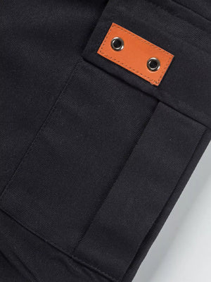 Black cargo shorts detail with tan leather patch and grommets.