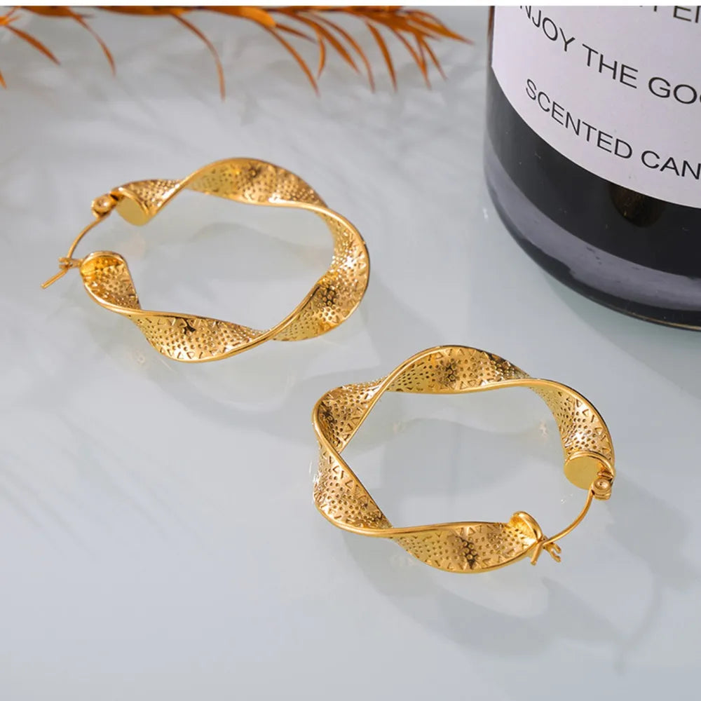 Textured spiral gold hoop earrings with a twisted design and perforated pattern.