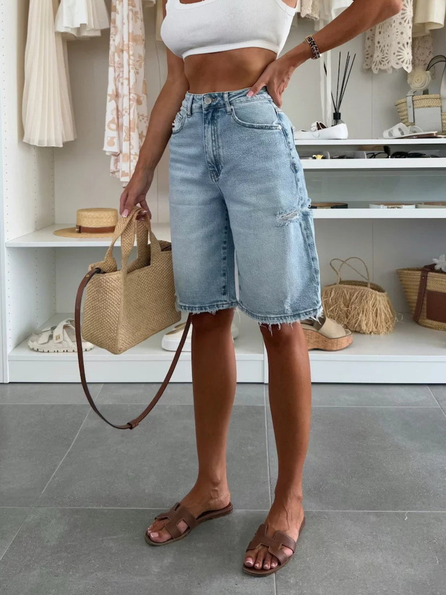 Distressed light wash denim bermuda shorts with raw hem and high waist.