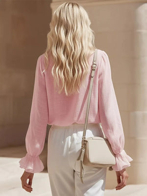 Pink maternity shirt with ruffled cuffs and long sleeves, styled with white pants.