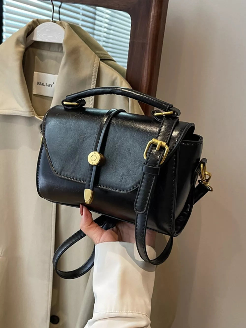 Mini black pu leather crossbody bag with gold clasp and adjustable strap.