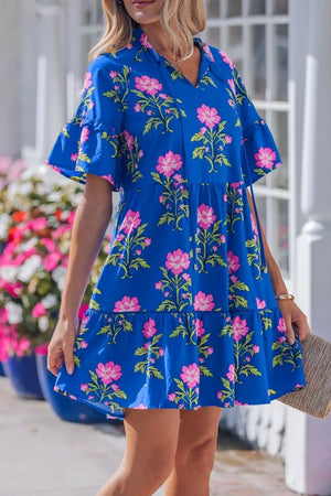 Blue tiered floral cotton dress with flutter sleeves and tie neck.