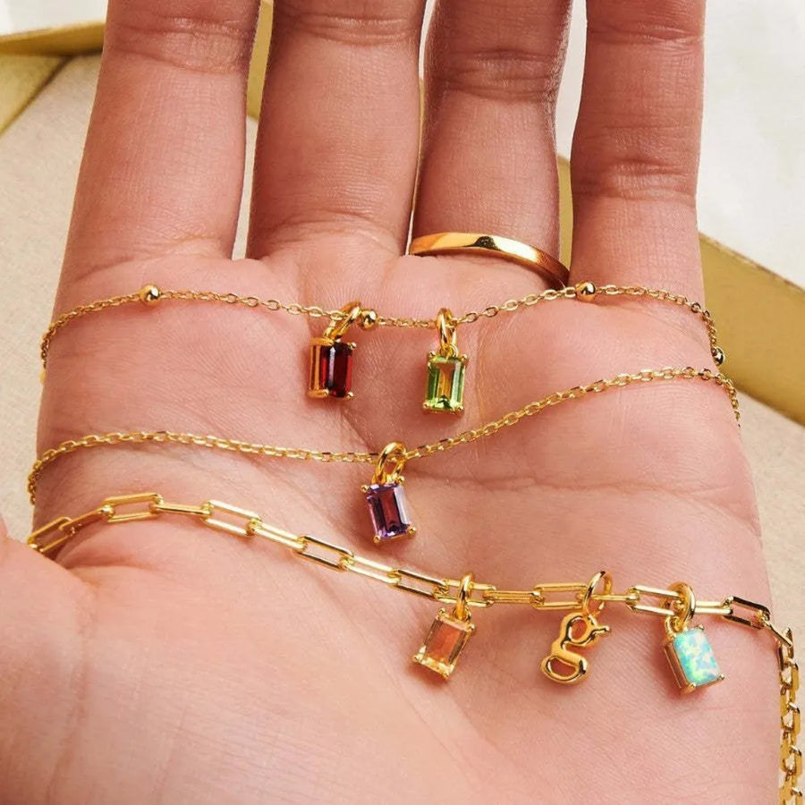 18K gold necklaces with colorful prism cut gemstones and letter charms.