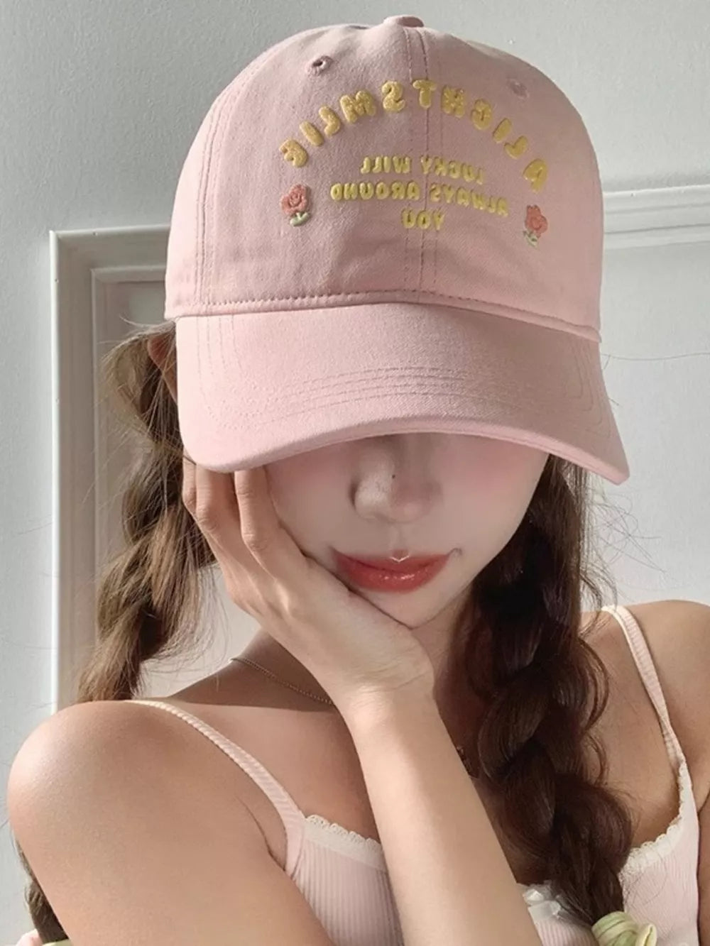Pink baseball cap with yellow embroidered text and rose details