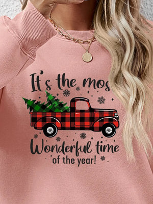 Blush pink sweatshirt with a graphic of a red plaid truck carrying a Christmas tree and holiday text.