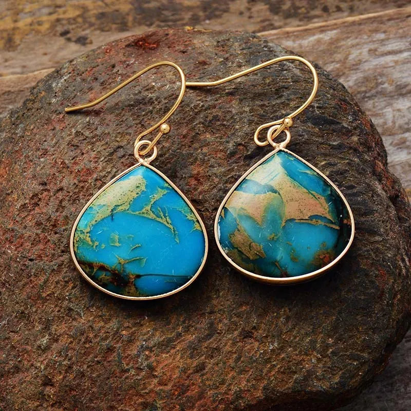 Teardrop turquoise and gold dangle earrings with unique blue and tan stone patterns.