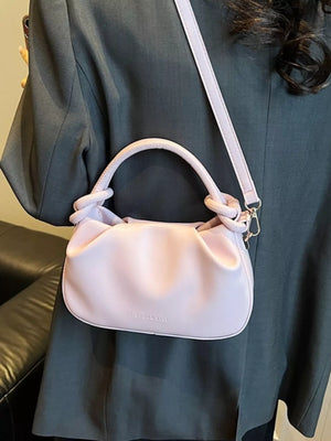 Pink ruched crossbody bag with knotted handles and a shoulder strap