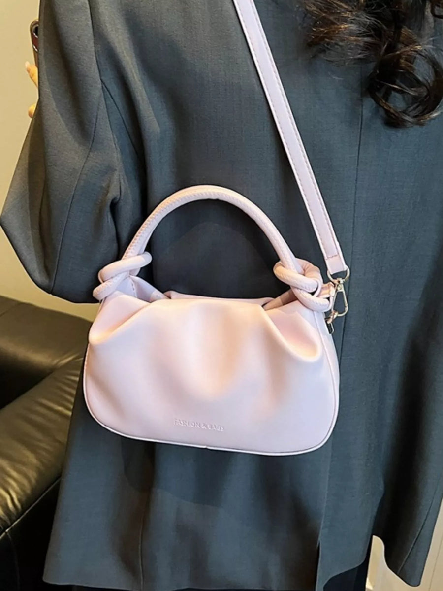 Pink ruched crossbody bag with knotted handles and a shoulder strap